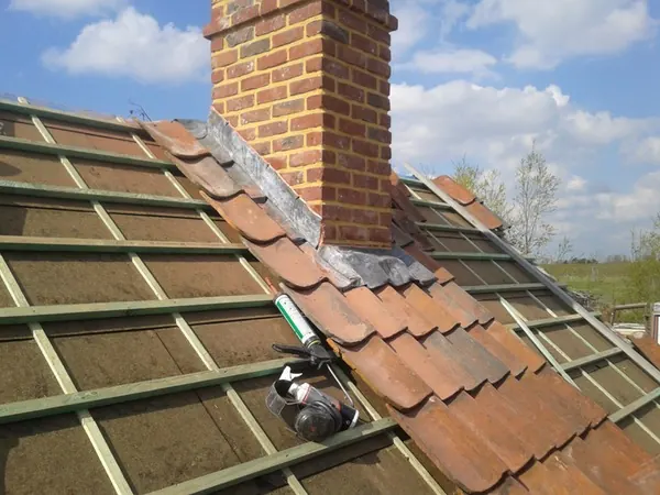 Hellend dak met dakpannen en een schouw tijdens de renovatie
