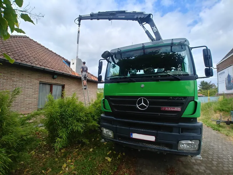 Groene vrachtwagen met kraan van De Longie tijdens hijswerken