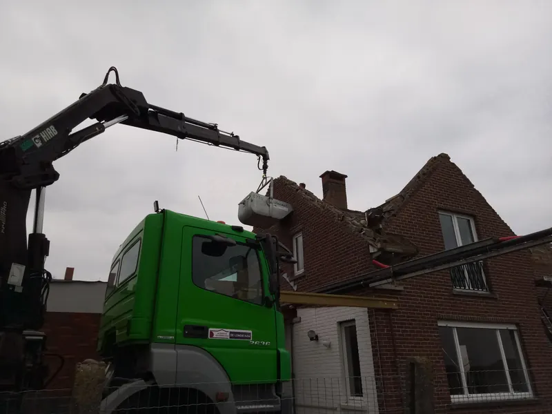 Vrachtwagen met kraan van De Longie bij een woning
