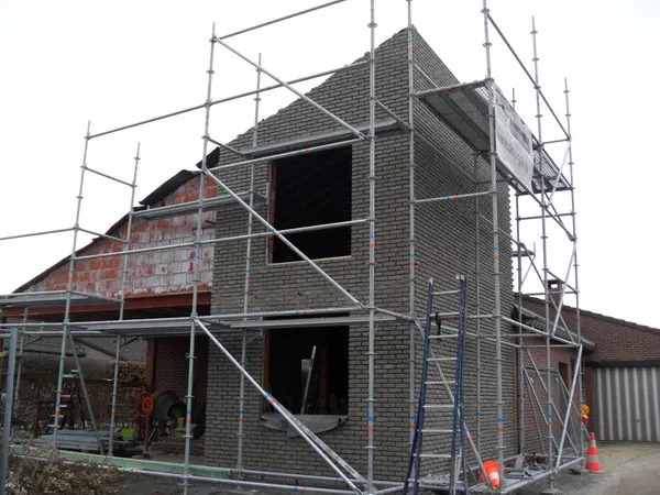 Woning in ruwbouw met steigers rond de gevel